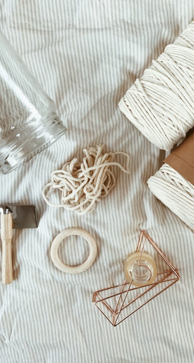 Matériaux d'artisanat : ficelle, corde, ciseaux, anneau en métal sur tissu beige.